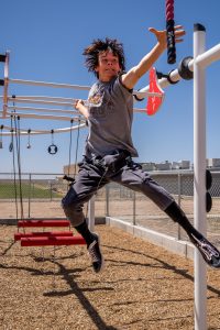 A teen boy reaching to grab a Swinging Rope on an X-Treme Ninja Course