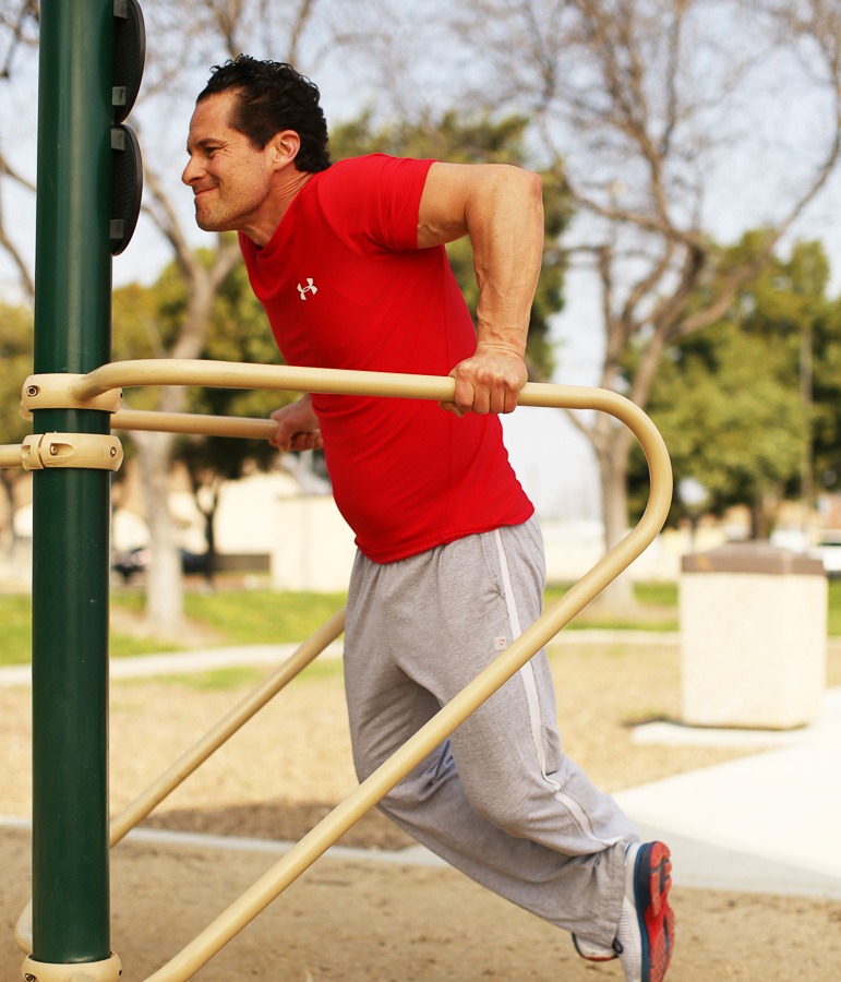 A man doing dips on dip bar.